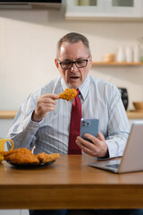 Lifestyle people, Mature male working sitting in the kitchen. with laptop and documents on desk, small business owner working online.