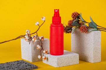 Cosmetic red bottle. Womens cosmetic accessory for makeup with stylish props on yellow background.