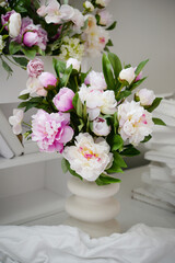 beautiful bouquet of soft pink and white peonies and small white flowers arranged in a simple white vase