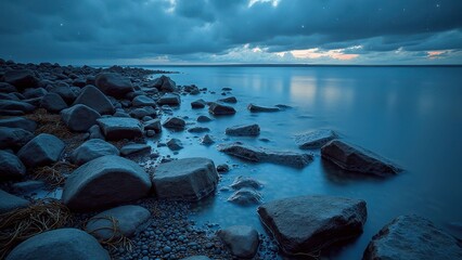 Tranquil ocean shoreline at dusk with dramatic cloudy sky and smooth rocks