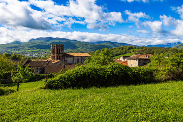 Romanesque cathedral of Saint-Lizier and its hexagonal brick bell tower with the green mountains of the Couserans in the background in spring