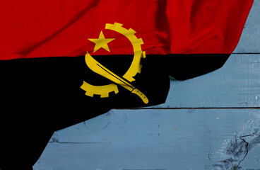 Angola national flag textile fabric waving on wood table