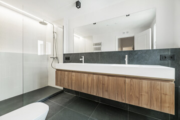 Contemporary designer bathroom with large frameless mirror, green marble on the wall