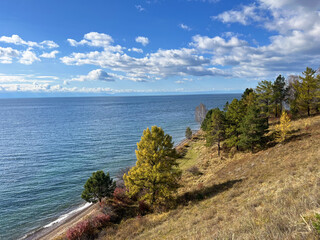 Obraz premium Scenic autumn landscape at lake baikal with vibrant foliage and tranquil waters under a clear blue sky for nature appreciation and travel inspiration