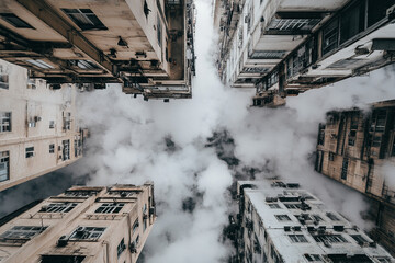 Fototapeta premium Industrial complex viewed from above with smoke billowing from stacks in urban setting