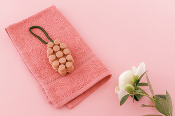 Towel with a soap and a peony flower on the pink background.