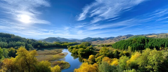 A river winds through a lush green valley with mountains and a bright blue sky under the sun.