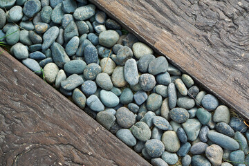 Background pattern: River pebbles of different sizes and shapes, with logs on either side.