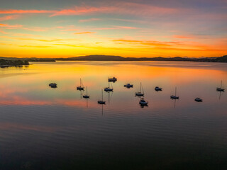 Naklejka premium Sunrise with high cloud, boats and reflections over the water