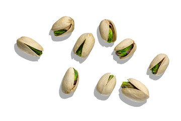 Roasted green pistachios in open shells on white background with shadow.