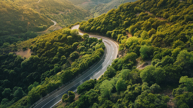 A serpentine road carves its path through a lush green valley, sunlight dappling the hillsides and hinting at the scenic journey ahead through the majestic landscape.