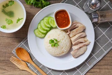 Chicken and rice with coriander and cucumber with sauce and soup in a white plate, hainanese chicken rice, thai called khao man gai, asian food, thai food