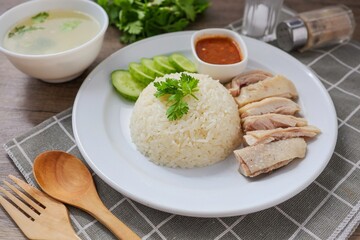 Chicken and rice with coriander and cucumber with sauce and soup in a white plate, hainanese chicken rice, thai called khao man gai, asian food, thai food