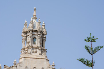 Fototapeta premium March 27 2022 - Spain. Baroque style tower with intricate carvings rises above the building, set against a clear sky and accompanied by a green branch, perfect for architecture or travel themes.