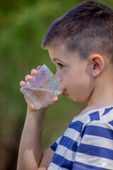Boy drinks water from a glass on a nature background.water.
