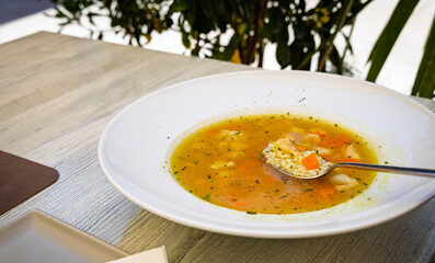 Traditional fish soup with rice, carrots, and herbs served in a white bowl. Light, flavorful seafood broth perfect as a warm and healthy starter.