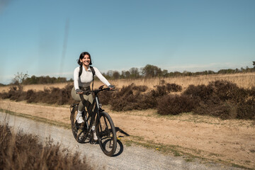Woman biking across sun-drenched dunes, combining cycling sport with relaxed beach travel and...