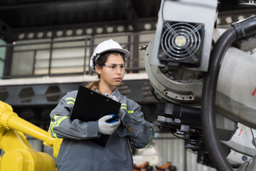 Automatic robotic arm, Storage warehouse. Woman engineer using clipboard check inventory robotics arms. Installation, testing or setting robotics arms