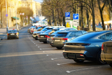 Fototapeta premium Parked cars, dense row of parked vehicles in angle position highlights the struggle of finding space in crowded urban downtown parking lot near public parks.