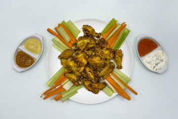 fried chicken legs with wings, asparagus and carrots on a plate on white background