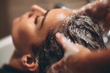 Close-up of a woman getting her hair washed at a salon, enjoying a relaxing scalp massage.