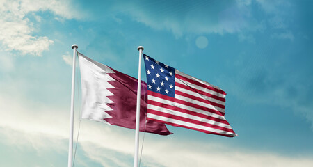 Qatar and America friendship flags are waving in the sky.Two country flag for agreement or deal....