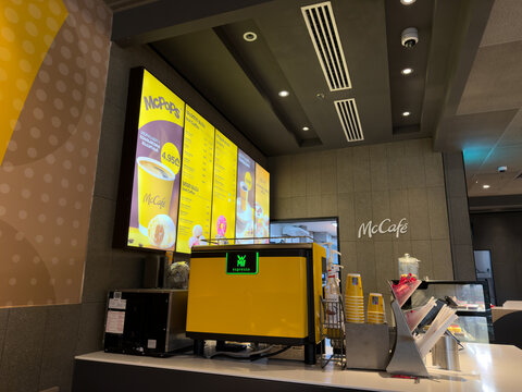 Tbilisi, Georgia, April 13, 2025: Interior of McCafe coffee counter with bright yellow espresso machine, digital menu board, branded cups and modern design elements in McDonalds coffee zone