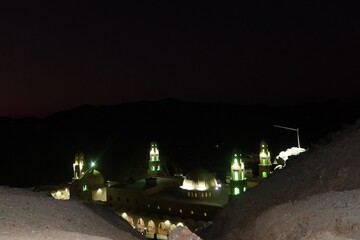 The ariel view at night of Aboul Hassan el Shazly Mosque in Homaithera in southern Egypt with its green lights shining the in middle of the hills and mountains