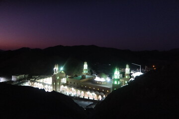 The ariel view at night of Aboul Hassan el Shazly Mosque in Homaithera in southern Egypt with its green lights shining the in middle of the hills and mountains