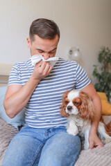 man holds tissues near his nose because of allergy to dog hair and looks upset. health concept