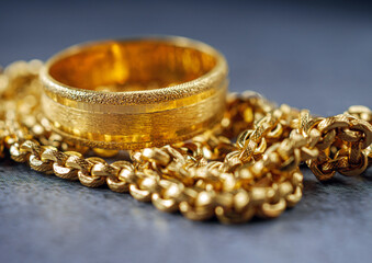 Gold price, gold jewelry, close-up of gold ring and gold necklace on grey background.
