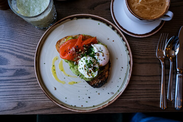 Healthy food. Toast with avocado, smoked salmon and poached eggs. Breakfast at lunch in a cafe