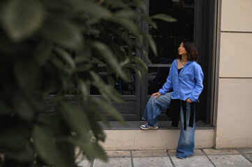 Stylish Asian woman posing on city streets in fashionable outfit. Confident urban look, modern...