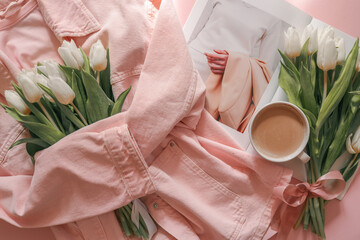 Flat lay with white tulips in a soft pink denim jacket, a fashion magazine, and a cup of coffee on a pastel pink background — cozy, stylish morning scene with feminine spring mood