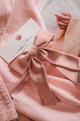 White tulips wrapped in a soft pink denim jacket with a satin pink hair bow on a card, styled on a...