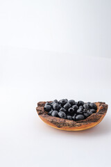 Rustic wooden bowl filled with glossy black olives placed on a clean white background. Minimalist food concept with natural textures and healthy organic snack