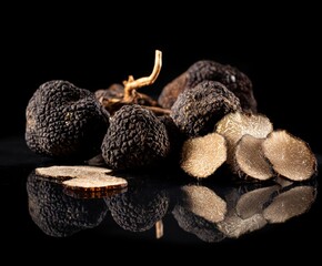 Black truffles and slices on black background