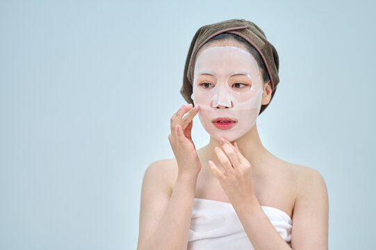 Young Woman Applying Sheet Face Mask for Hydration and Beauty