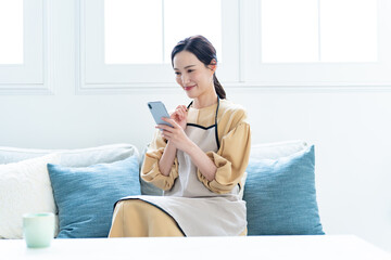 リビングのソファで携帯を触る女性