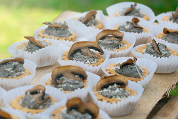 Savory mushroom tartlets with creamy filling on rustic wooden tray