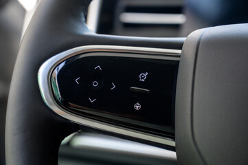 A close-up of a modern car's steering wheel with control buttons