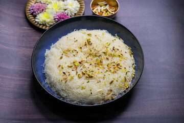 Closeup of Sutarfeni, a traditional Indian sweet made from fine sev soaked in sweet saffron flavored milk, garnished with dry fruits. Perfect for festive celebrations and Indian cuisine themes. copy
