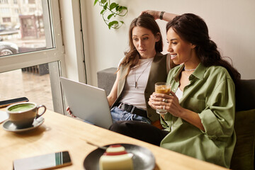 Two women share a joyful moment while enjoying drinks at a cozy cafe during a rainy day