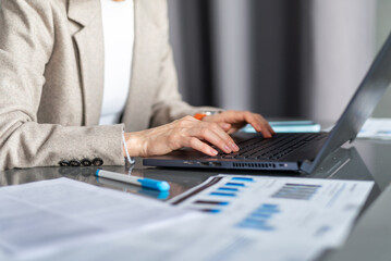 Woman working with laptop and documents analyzing data or writing reports Workplace office or home