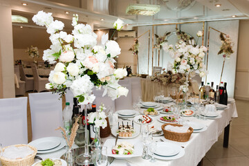 A beautifully decorated wedding reception table features a stunning white floral arrangement,  appetizers, and glassware, creating a sophisticated and romantic ambiance.