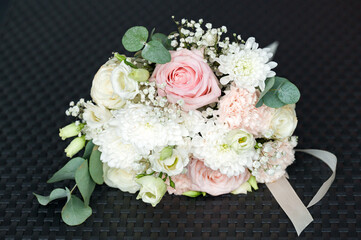 A stunning bouquet featuring a mix of pink and white roses, chrysanthemums, and other delicate blooms.  The arrangement is beautifully composed and rests on a dark surface.