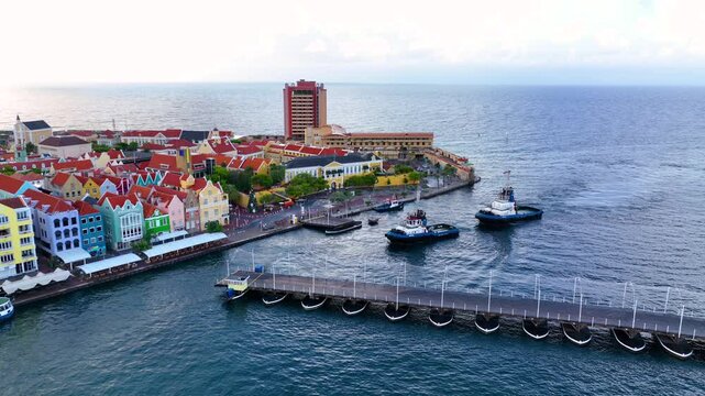 Tugboats sail on Sint Anna Bay, with Queen Emma Bridge (Koningin Emmabrug) swing to open, Willemstad historic city center, Curacao. Historic Willemstad is a UNESCO World Heritage Site. 