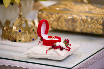 Close-up of wedding rings nestled in a red velvet box, adorned with flowers and placed on a...