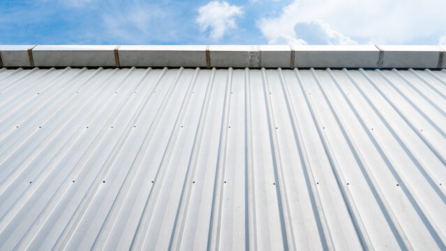 Wall of bronze metal sheet roof. Basic color of matal sheet. Drainage channel fixed at the top. Blue sky and white clouds for background.