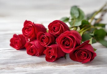 Obraz premium A beautiful bouquet of red roses lies on a rustic wooden surface, displaying elegance and romance.
